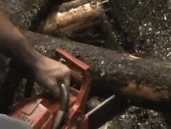 Close Up hand-held tilt-down tilt-up zoom-in - A mechanic cuts up logs with a chainsaw in a pulping machine / Borlange, Sweden Stock Footage