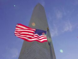A static shot with a lens flare of flags waving in the wind in front of the Washington Monument. Stock Footage