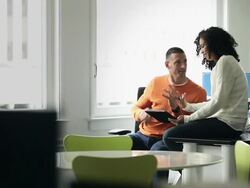 MS TU PAN businessman and businesswoman sitting at workstation in office working on digital tablet  Stock Footage