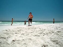 Slow motion low angle man running on beach and diving toward CAM to head soccer ball Stock Footage