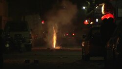 Fireworks explode next to parked cars on a street in Beijing. Stock Footage