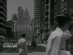 1966: SAO PAULO, BRAZIL: HA XWS Cityscape w/ bridge & wide street, traffic, skyscrapers. Angled WS Street scene w/ pedestrians crossing FG, traffic passing down & out of frame. VS People walking across intersection, cars turning. Urban, modern, city Instructional Video