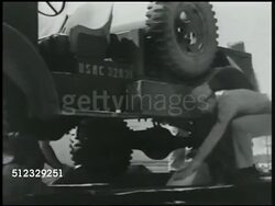 1942: U.S. MARINES: TRANSPORTING: WS Military jeep driving up ramp onto train flat bed. MS Soldiers securing jeep w/ wheel wedges. WS Jeeps on train. MS Man hammering wooden pieces behind wheel. WS Men securing wedges on heavy tank base, wheels. Instructional Video