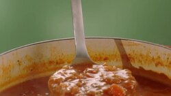 ladle scoops out a hot serving from large pot of chili and chili bowl Stock Footage