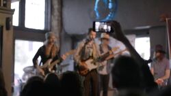 Young man raises arm above crowd to snap photo of band with smartphone Stock Footage