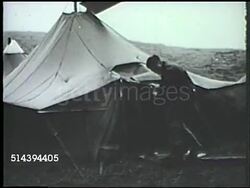 1943: ALEUTIAN ISLANDS CAMPAIGN: UNITED STATES ARMY: VS U.S. Army camp tent being blown by strong winds at Amchitka, Alaska, soldier fastening down tent, shelter, tents blowing in winds. WWII, World War II, Pacific Front, camp life, weather Instructional Video