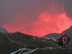 Climber rests on cliff above erupting lava lake, Marum Volcano, Ambrym Island, Vanuatu Stock Footage