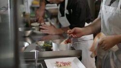 Gourmet chef places steaming lobster on bed of scallops in busy kitchen restaurant Stock Footage