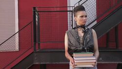 Cool young woman holding stack of books at urban stair Stock Footage