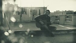 Hipster man playing acoustic guitar on the terrace: monochrome video Stock Footage