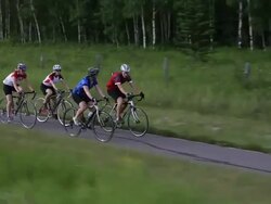 Track view of biking peloton of 4 bikers following forest path Stock Footage