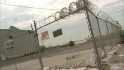 Coiled barbed wire tops a chain-link fence around a power plant. Stock Footage