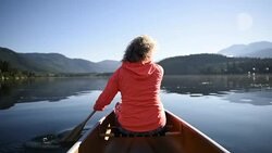 Senior Woman canoeing on a pristine lake Stock Footage