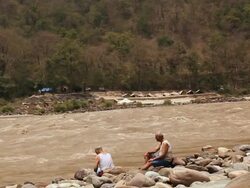 Two senior men sitting at riverbank, Ganges River, Rishikesh, Uttarakhand, India Stock Footage