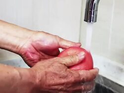 Old man washes apples in his kitchen Stock Footage