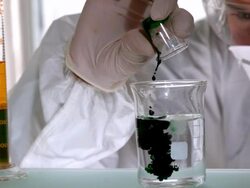Scientist mixing and pouring liquids in beaker Stock Footage