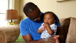 MS ZI Father holding laughing infant son on lap in living room Stock Footage