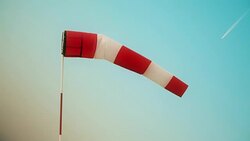 Windsock against blue sky and airplane Stock Footage