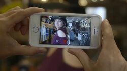 camera films phone while girl tries on hat for fashion blog Stock Footage
