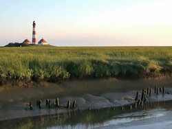 WS View of Westerhever lighthouse from dry river and green grass field / Westerhever, Schleswig Holstein, Germany Stock Footage