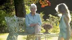 Grandmother watching granddaughter doing cartwheels in sunny garden Stock Footage