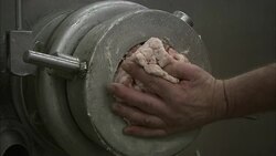 A meat grinder operates in s sausage making plant where a technician extracts ground meat. Stock Footage