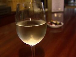 Glass of Chilled White Wine Sitting on Bar Top News Clip