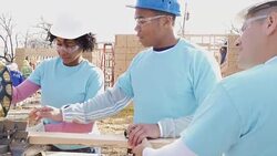 Volunteer construction foreman teaching woman how to use miter saw Stock Footage