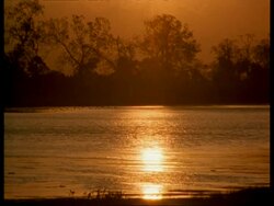 WA Orange sunlight reflecting on water hole at dusk, India Stock Footage