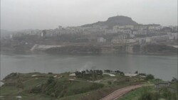 A tiered green-roofed temple overlooks a river. Stock Footage