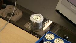 A hand with latex finger cots places watch components on a machine at a watchmaking factory. Stock Footage