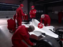 Medium shot view of mechanics working on Formula One race car in garage / zoom in crew member wiping down car Stock Footage