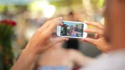 Cute Brazilian girl laughs and poses for smartphone photos with bouquet of flowers in bustling Rio marketplace Stock Footage