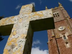 T/L cloud shadows passing over lichen-covered cross and church tower, UK Stock Footage