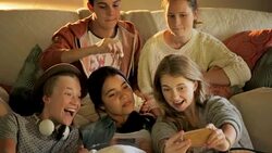 Teenage friends eating popcorn and watching TV in living room Stock Footage