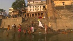 Men and boys bathe in a river at the bottom of a set of stairs. Stock Footage