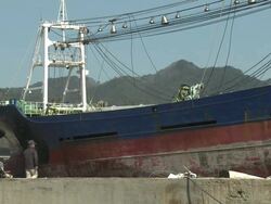 Large ship rests amoung burnt out area of Kessenuma city after huge fire during tsunami.  filmed on 1 April 2011, 3 weeks after tsunami which was caused by magnitude 9 Tohoku earthquake off north east Japan / AUDIO Stock Footage