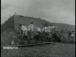 1943: WWII GERMAN FORTIFICATIONS: Male workers shoring up exterior wall of bunker w/ wheel barrows of dirt. German Nazi officer in structure (beyond beachfront) using binoculars mounted on tripod. (possibly France hilltop above beaches) Instructional Video