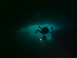 Cave entrance, diver with lights swim away into cave, camera . Borneo, Malaysia, Southeast Asia Stock Footage