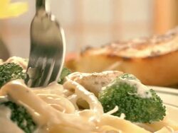 CS PAN  from wine bottle and toasted garlic bread to steaming plate of chicken broccoli pasta alfredo as fork lifts noodles from plate  Stock Footage