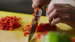 Chef's hands finely dice red pepper in restaurant kitchen Stock Footage