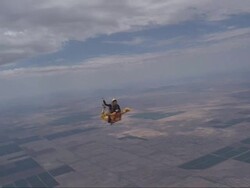Two skydivers in a rodeo dive, with one riding on top of the other's back.  Another skydiver flies around them. Stock Footage