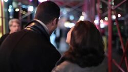 Young couple walk arm-in-arm down busy sidewalk, marvelling at the sights and sounds of Times Square; girl kisses boyfriend on cheek Stock Footage