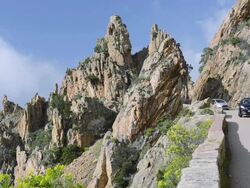 MS Shot of Cars on the road through the fantastic rock landscape of the Calanche of Piana, UNESCO World Heritage Site / Gulf of Porto, Corsica, France Stock Footage