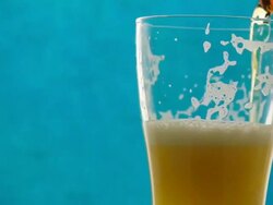 Pouring beer into rotate glass on blue background Stock Footage