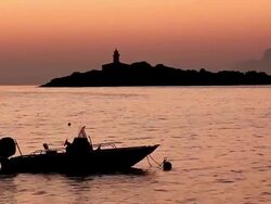 WS VIew of One motarboat floating on water in front of lighthouse / Mallorca, Balearic Islands, Spain  Stock Footage