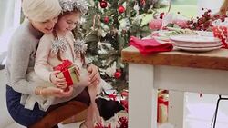 Mother and daughter with Christmas gift watching Jack Russell terrier enter window Stock Footage