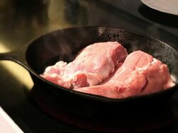 Woman is cooks a ham in a cast iron pan Stock Footage