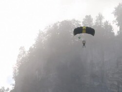 BASE jumper/wing suit flier descends from cliff Stock Footage