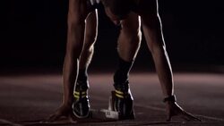 An athlete crouches at the starting blocks on a track before running and practicing jumping jacks. Stock Footage
